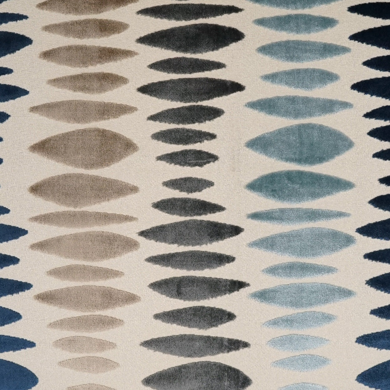 Fabric featuring vertical rows of teardrop-shaped oval motifs in taupe, charcoal and blue on a beige background.