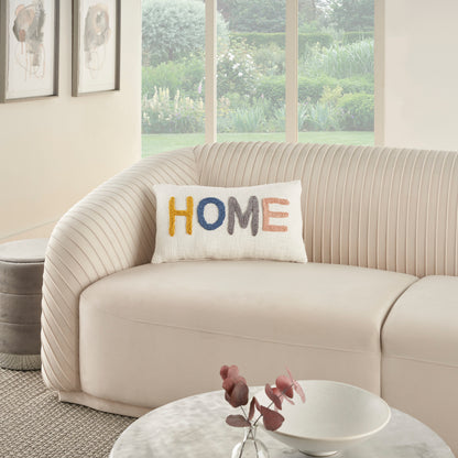 Cream curved sofa with ribbed back, colorful 'HOME' embroidered pillow, round marble coffee table, soft neutral living room.