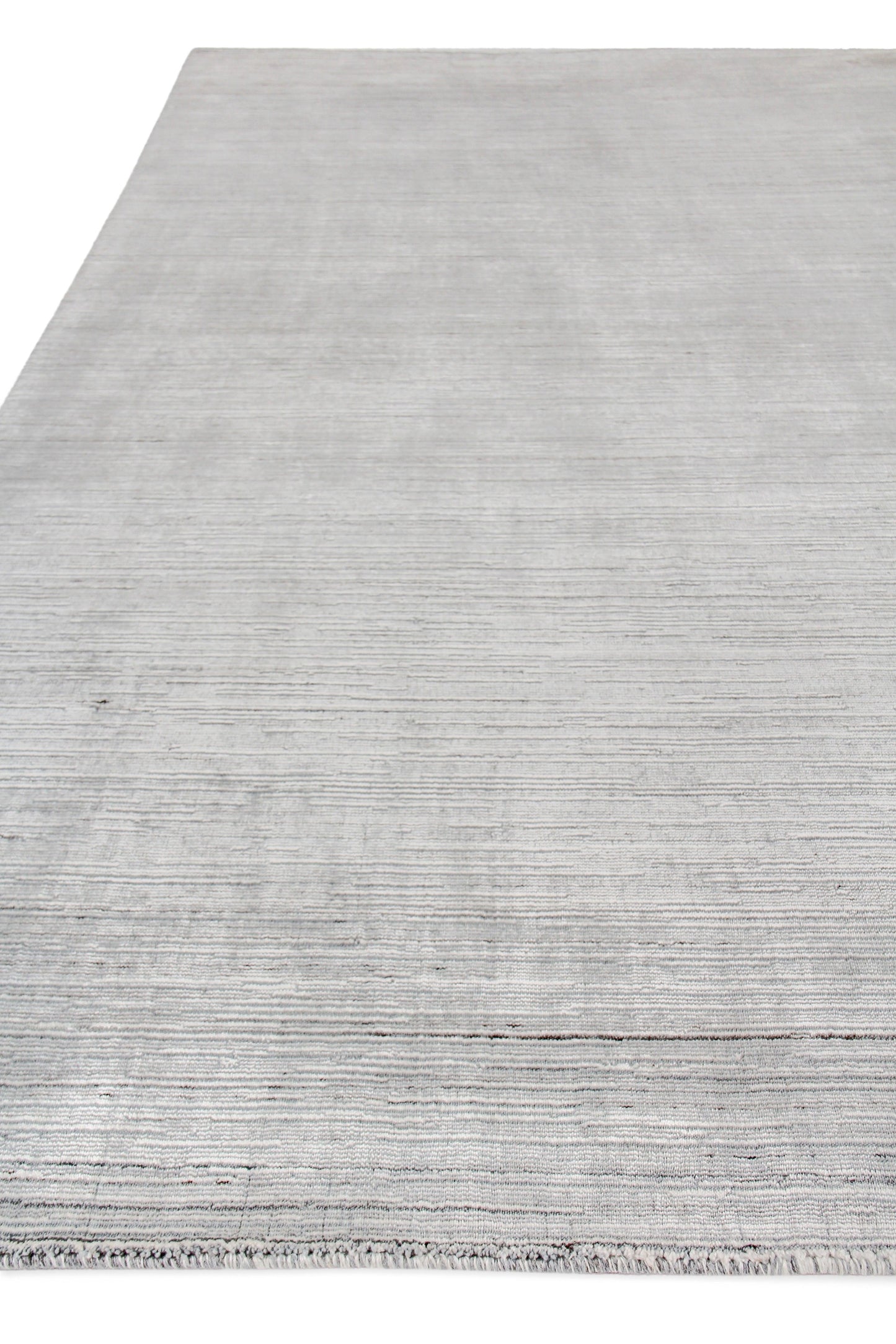 Light gray hand loomed indoor rug with subtle horizontal stripes & fringed edge for modern living spaces.