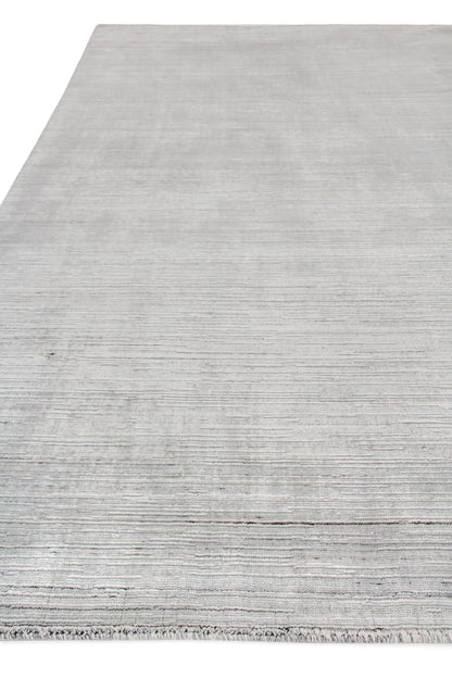 Light gray hand loomed indoor rug with subtle horizontal stripes & fringed edge for modern living spaces.