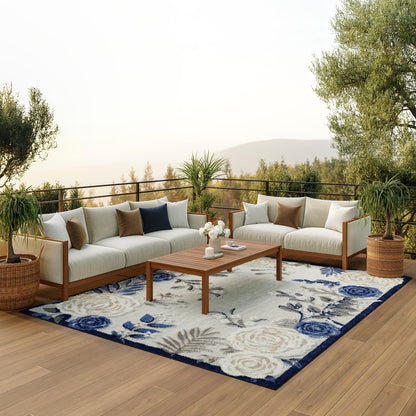 Blue floral outdoor rug on a deck with a coffee table, potted plants & a scenic deck view.