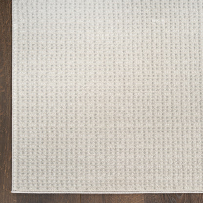 Beige textured woven fabric swatch with subtle grid pattern on a wooden floor.