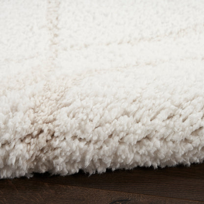Cream shag rug with dense plush pile resting on dark wooden floor.