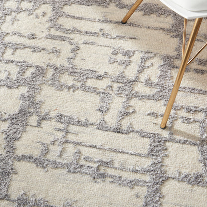 Cream and gray geometric shag rug with a soft fluffy pile; wooden chair legs rest on its patterned surface.