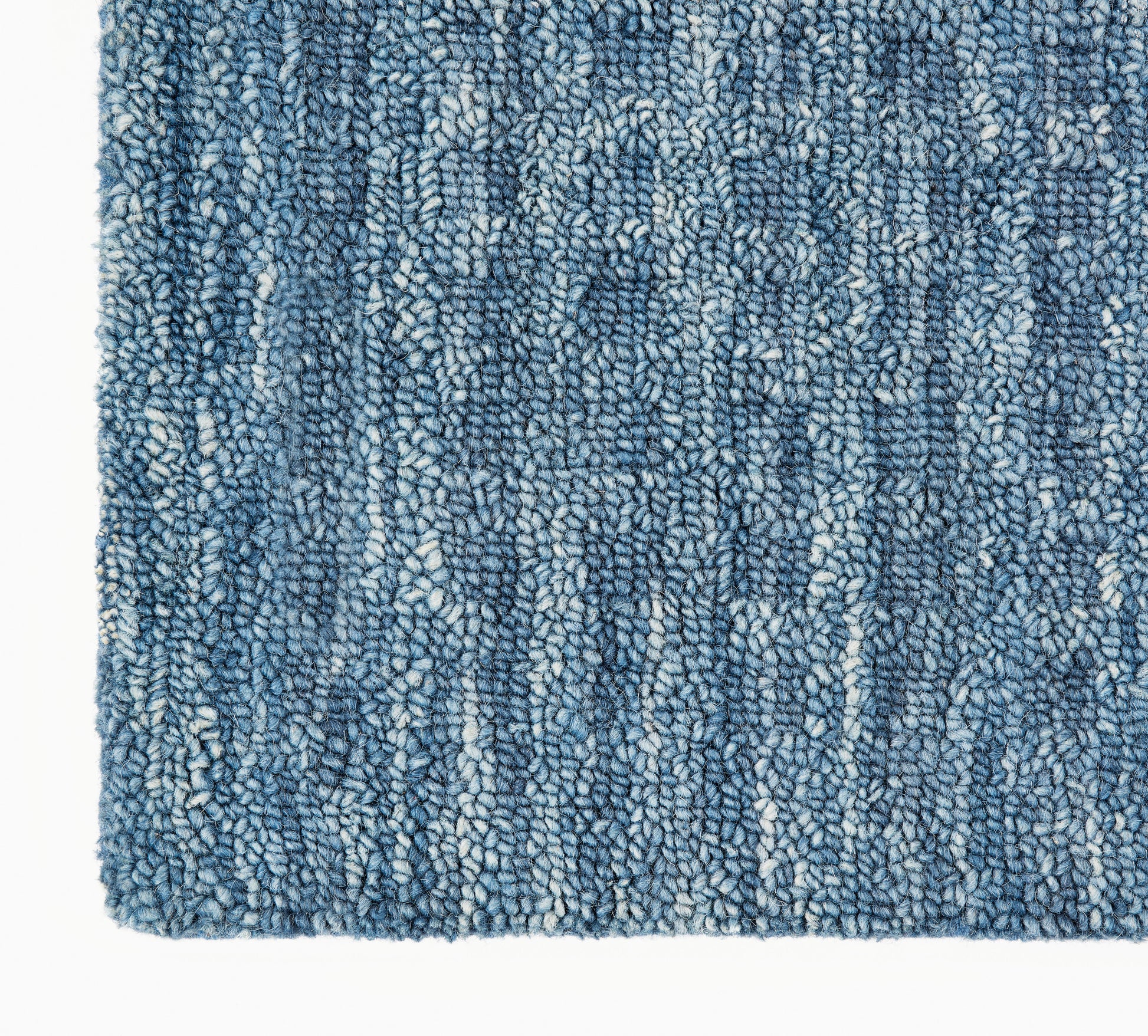Blue textured shag rug close-up with indigo and light blue loop pile; plush, cozy floor decor.