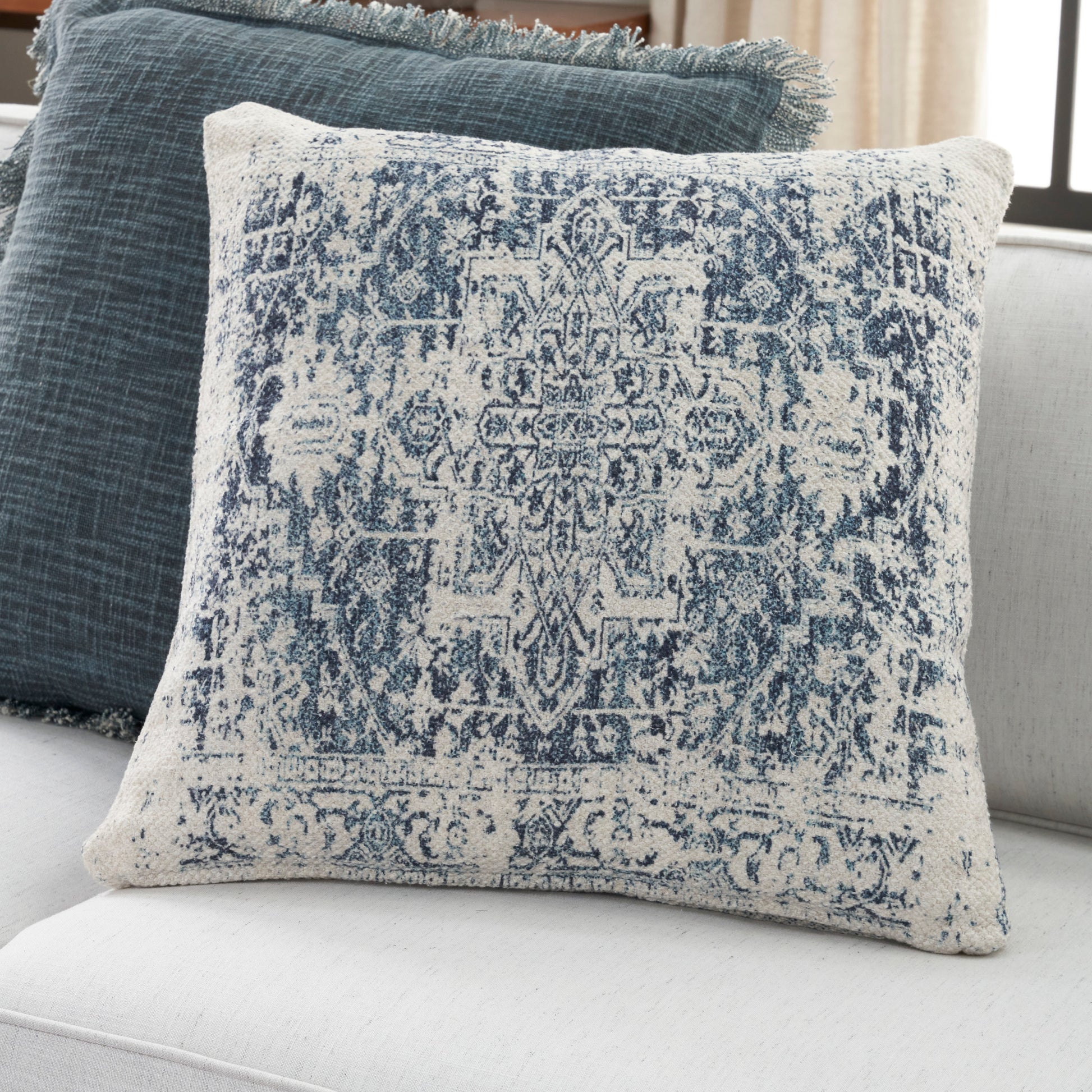Square ivory pillow with distressed indigo rug pattern, woven cotton, decorative for sofa or bed.