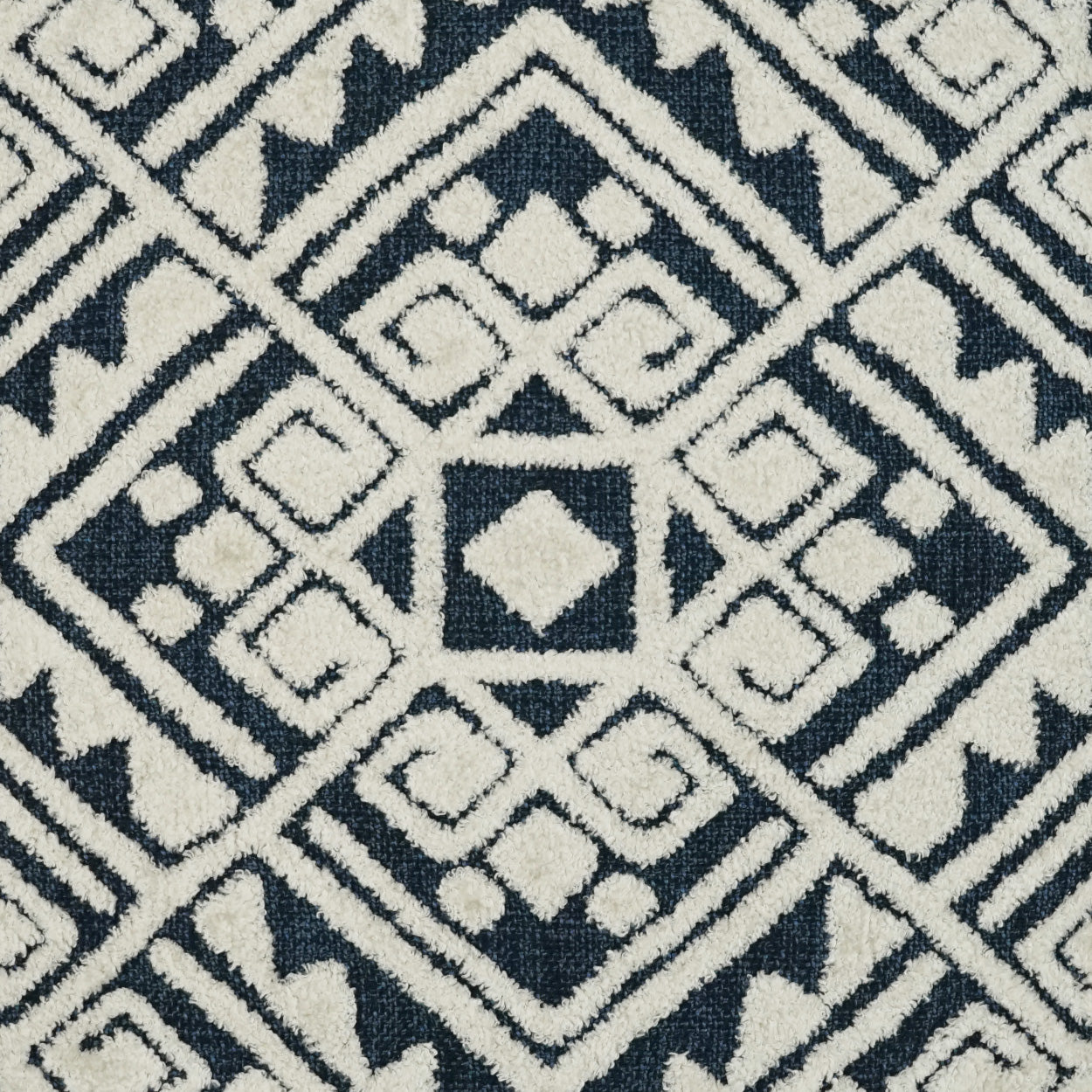 Gray fabric swatch, square, atop a navy blue and white geometric rug.