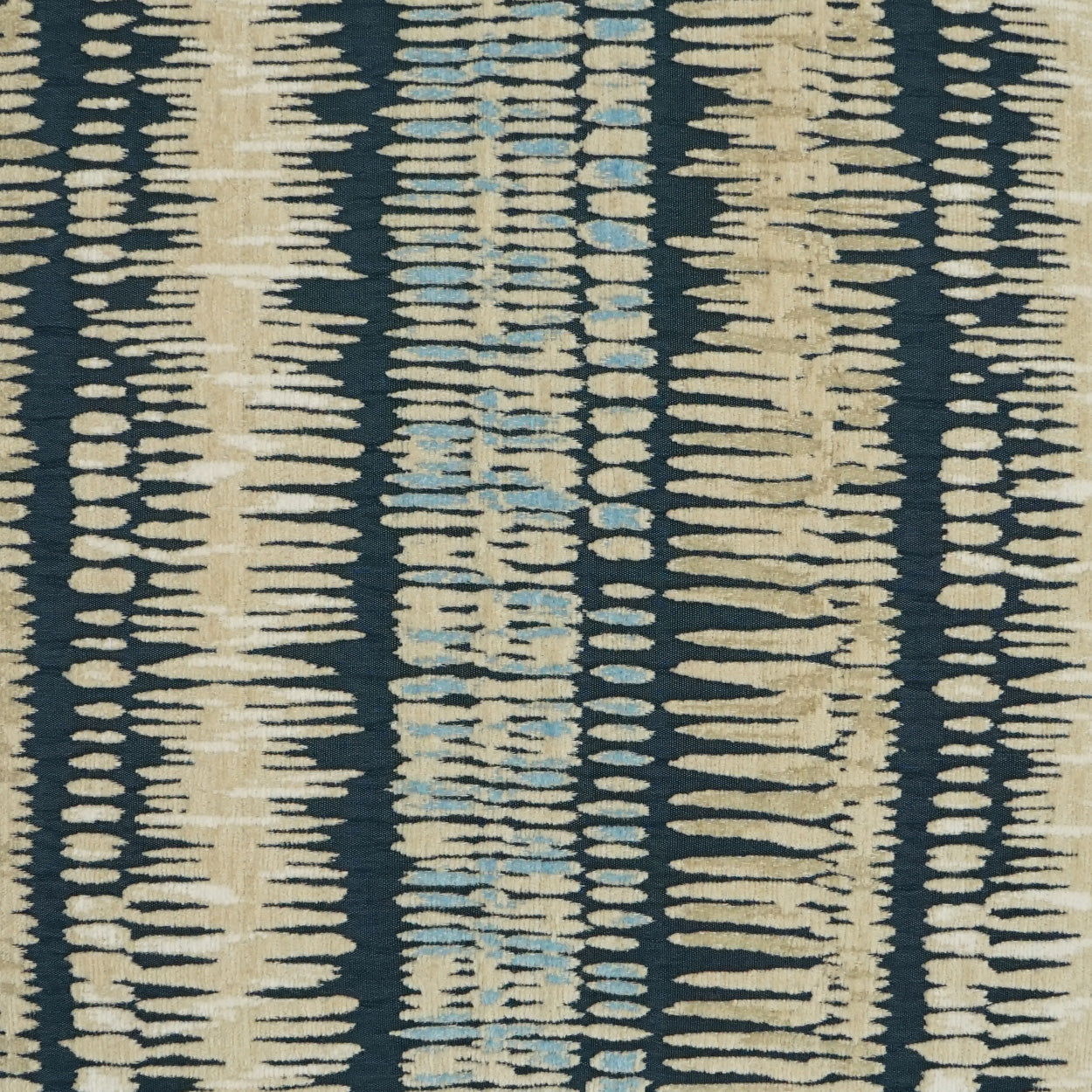 Ikat-inspired striped fabric with beige and light blue dashes on a dark navy background; woven upholstery textile.