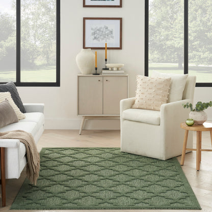 Green textured geometric area rug in a bright living room with cream sofa, beige armchair, light wood cabinet, and plant.