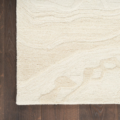 Cream textured area rug with a subtle wave pattern on dark hardwood floor; plush tufted style.