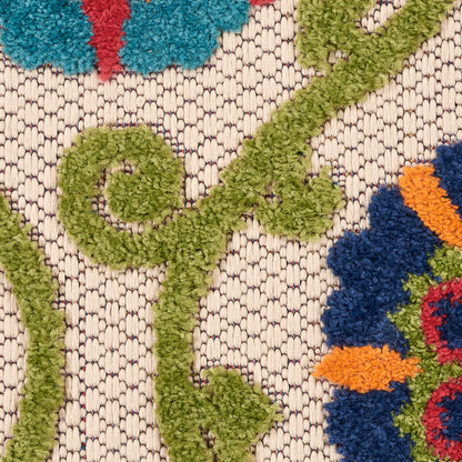Close-up of a textured woven rug with green tufted vines and multicolored floral motifs on a beige background.