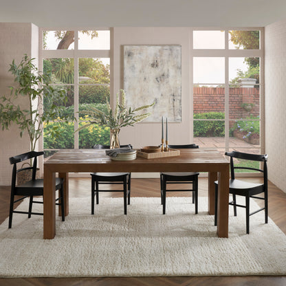 Cream shag rug under a rustic wooden dining table with black chairs, large windows with a garden view, abstract wall art.