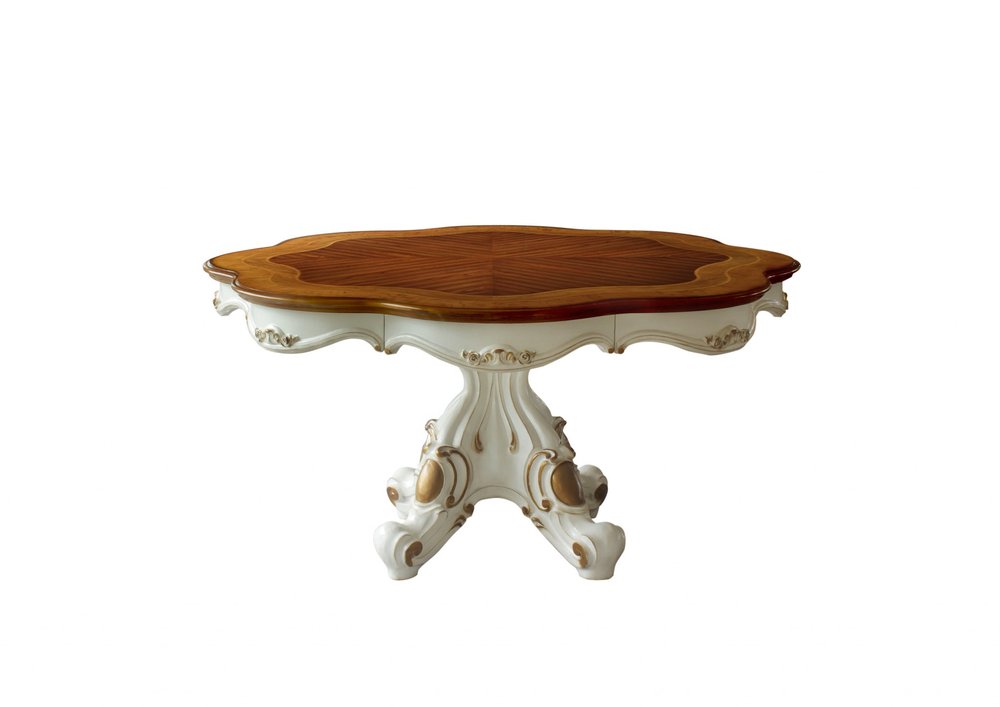 Ornate antique-style pedestal table with a cream carved base, gold detailing, and an oval natural wood top.