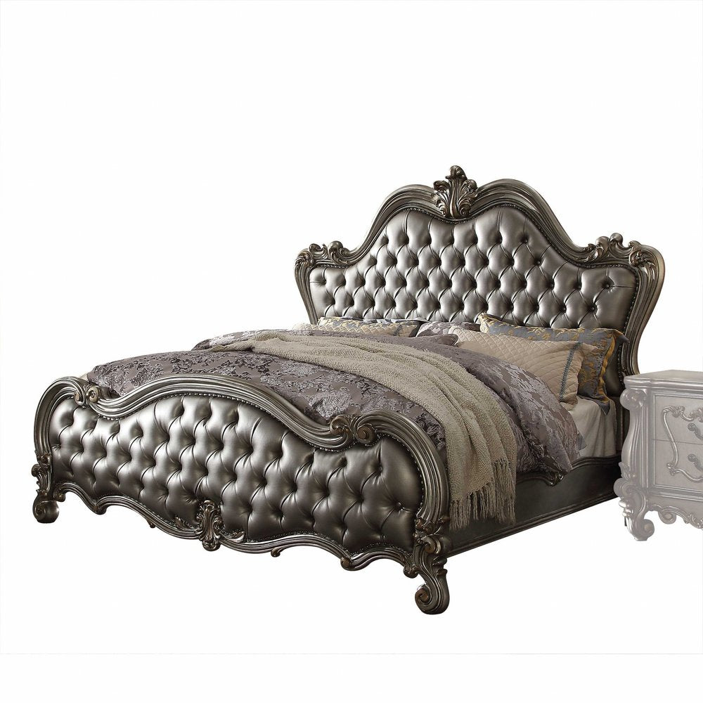 Metallic silver tufted king bed with ornate carved frame, arched headboard and footboard; grey bedding
