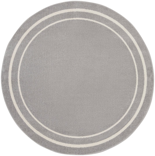Round grey rug featuring two white concentric rings along the border; soft textured surface.