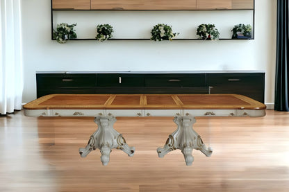 Ornate metal-pedestal dining table with a light wood top in a modern living space.
