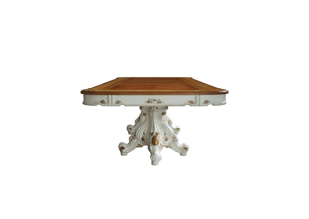 Brown and white solid wood dining table with a double pedestal base, ornate carved wood-inlaid rectangular top and gilded accents.