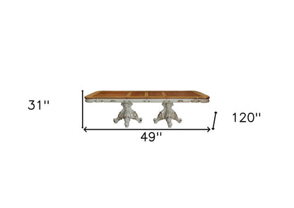 Rectangular brown wood dining table with ornate light-gray pedestal bases in antique style.