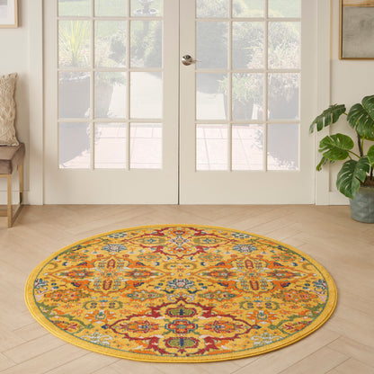 Round oriental rug in warm yellow with multicolor floral pattern on light wood floor by glass French doors.
