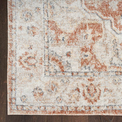 Ivory, rust & blue vintage Persian-style rug with medallion border on dark wood floor.