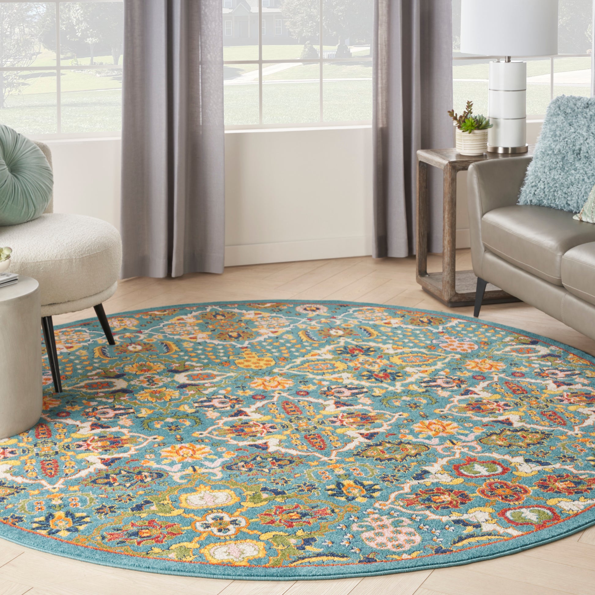 Round teal rug with a vivid multicolor floral pattern on light wood flooring in a modern living room.