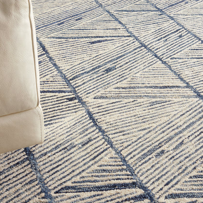 Beige leather sofa edge beside a blue geometric rug with triangular line patterns.