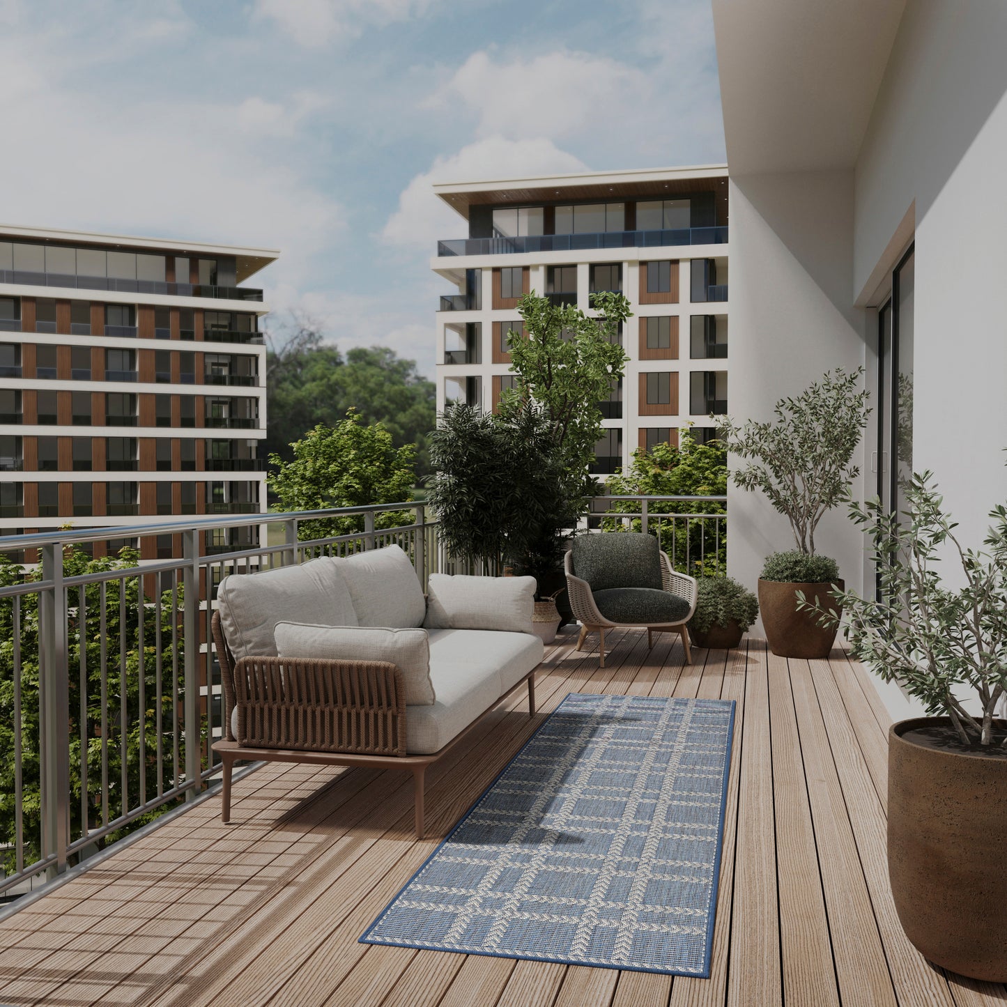 Outdoor balcony seating set with beige cushioned wicker sofa and chairs, blue geometric rug, wooden deck, potted plants.