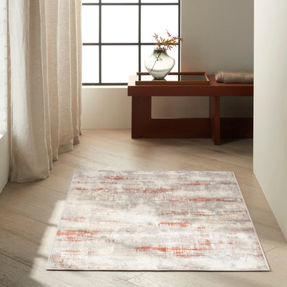 Rectangular area rug with light grey base and orange brushstroke accents in a bright, minimalist living space.
