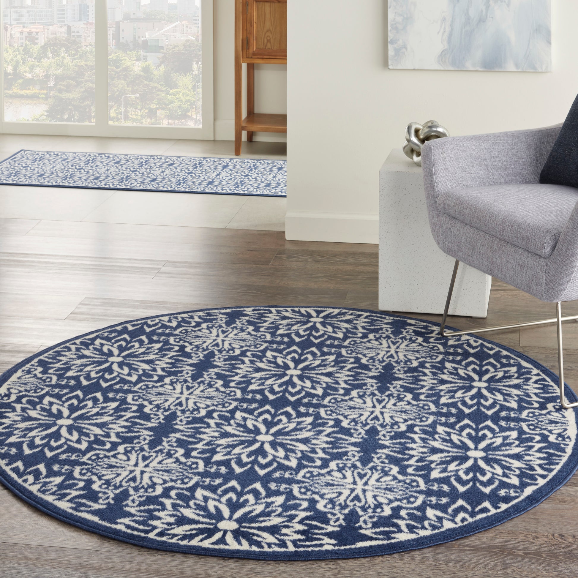 Round navy blue rug with a white floral geometric pattern; plush woven texture for modern living room decor.