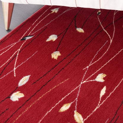 Red area rug with cream and yellow leaf motifs along slender white branches; modern botanical design.