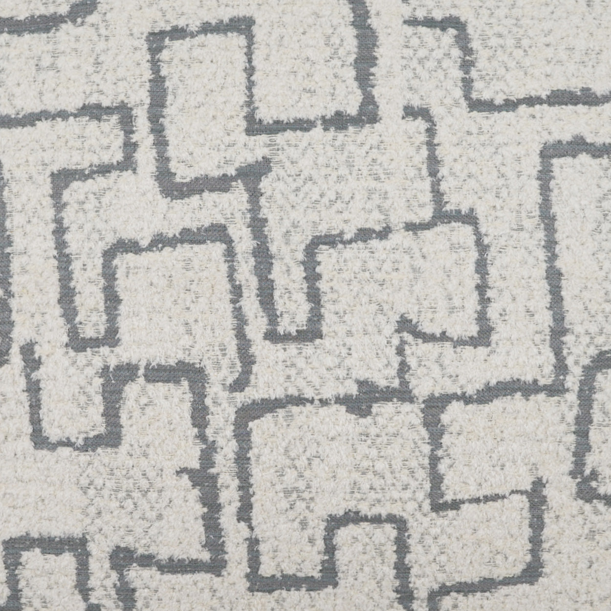 Grey pillow with a dark gray interlocking geometric square maze pattern.