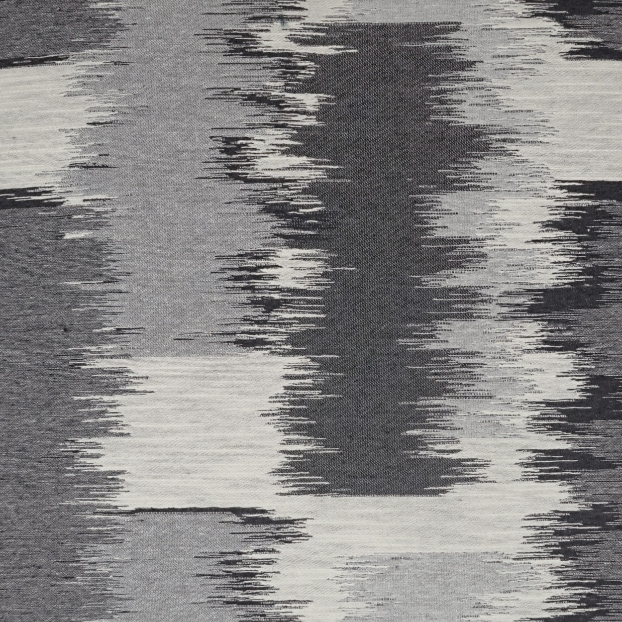 Gray-scale woven fabric with abstract zigzag blocks in charcoal, gray, and ivory; versatile upholstery or drapery textile.