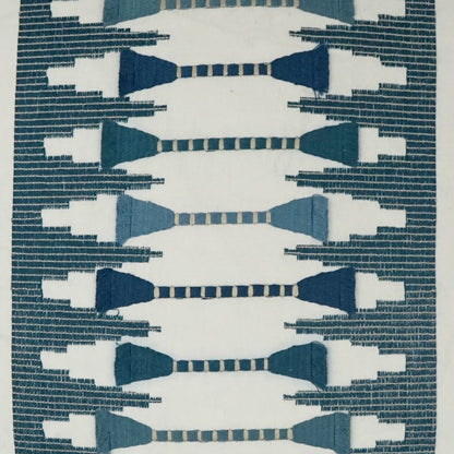 Geometric embroidery on a cream pillow with navy & teal bow-tie motifs and a dark teal border.