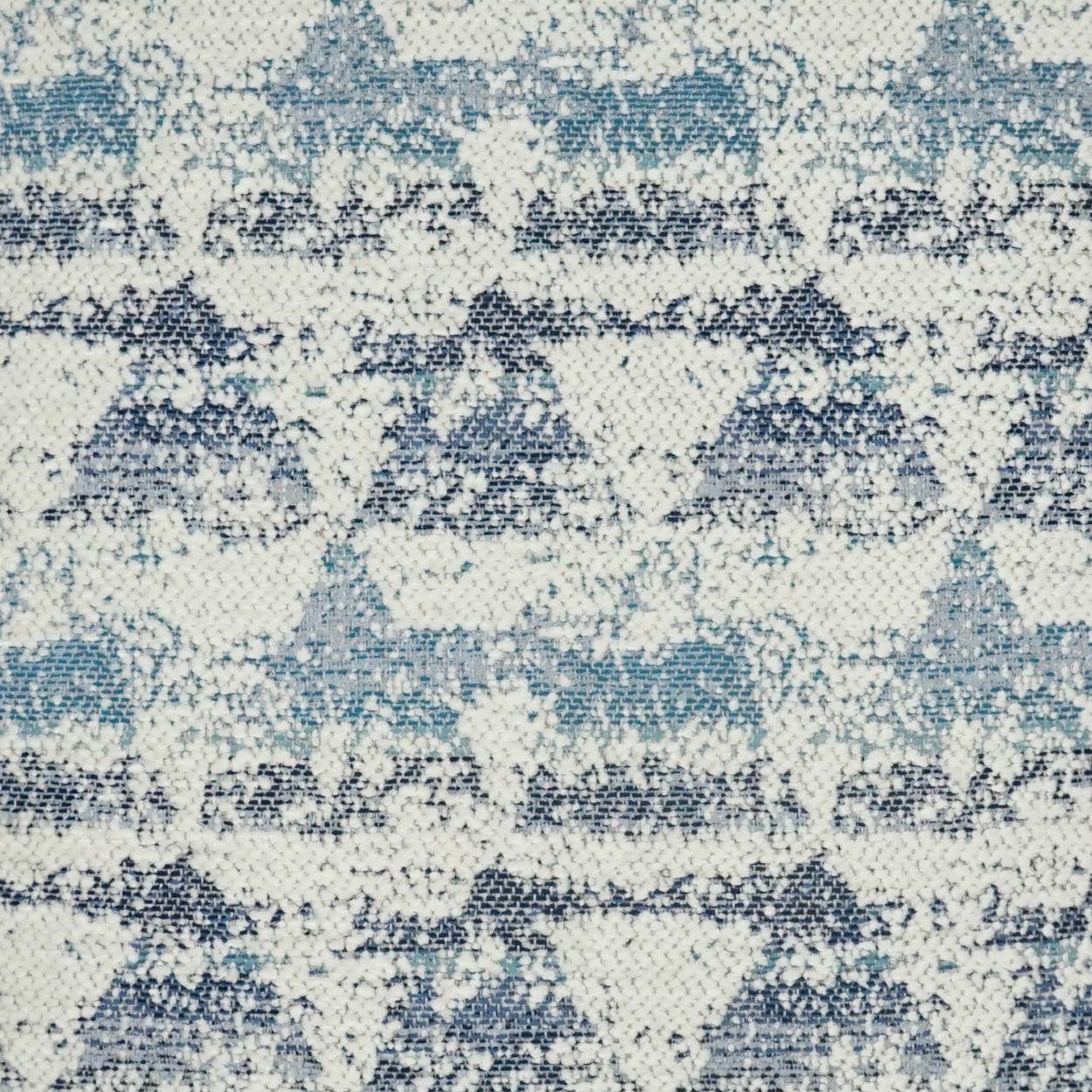Cream fabric with blue, teal and navy geometric diamonds and zigzags; woven textile pattern on a 24" x 24" pillow.