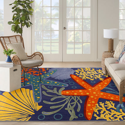 Coastal blue outdoor rug with orange starfish and yellow coral on a sunlit patio with wicker chairs.