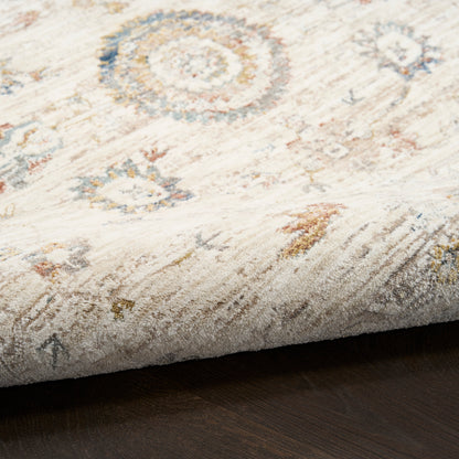 Cream distressed area rug with blue, amber and gray circular medallions on a dark wood floor.