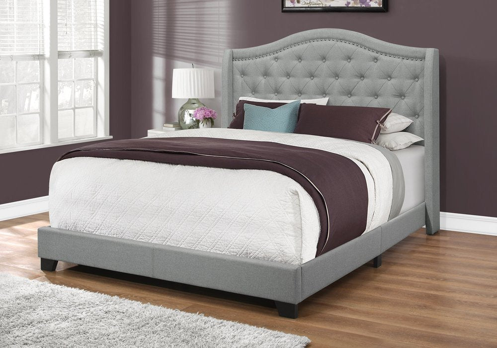 Solid wood queen bed with tufted gray linen upholstery and nailhead trim.