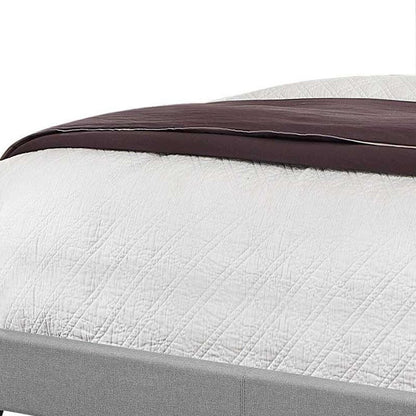 Solid wood queen bed with tufted gray linen upholstery and nailhead trim.