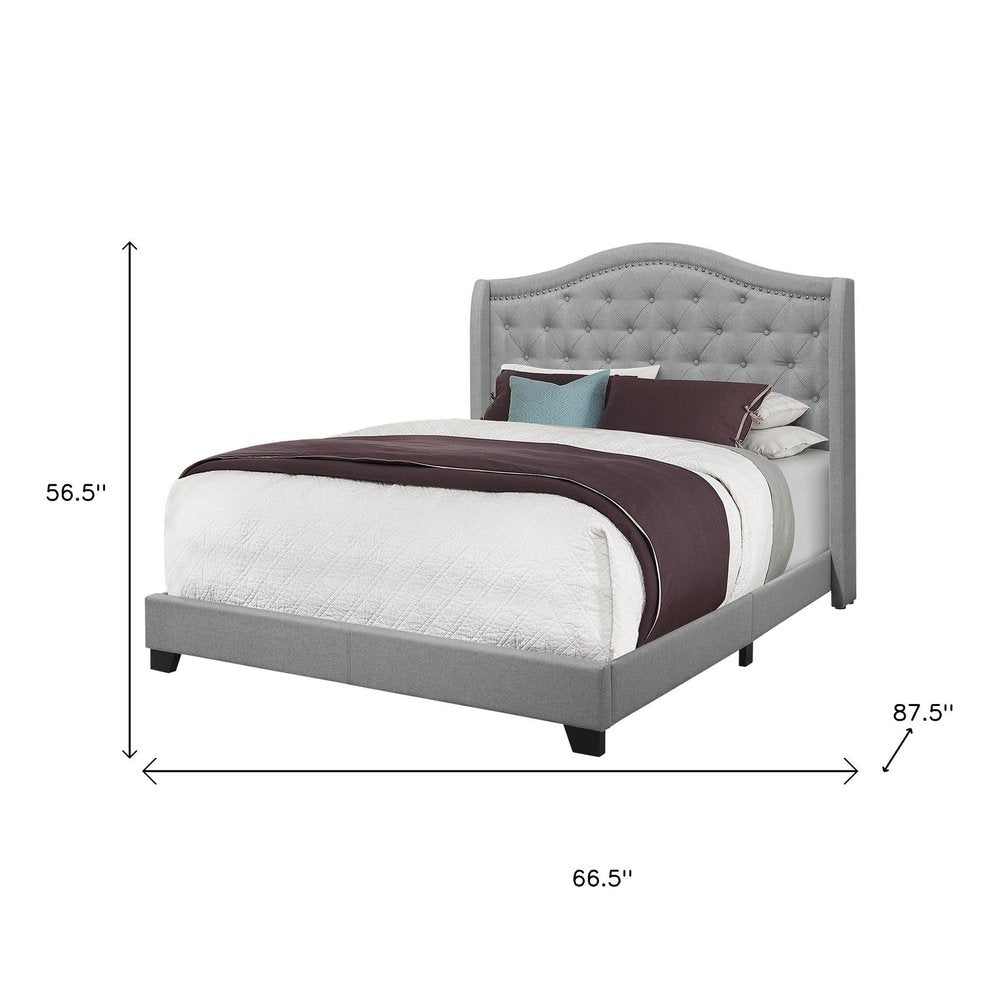 Solid wood queen bed with tufted gray linen upholstery and nailhead trim.