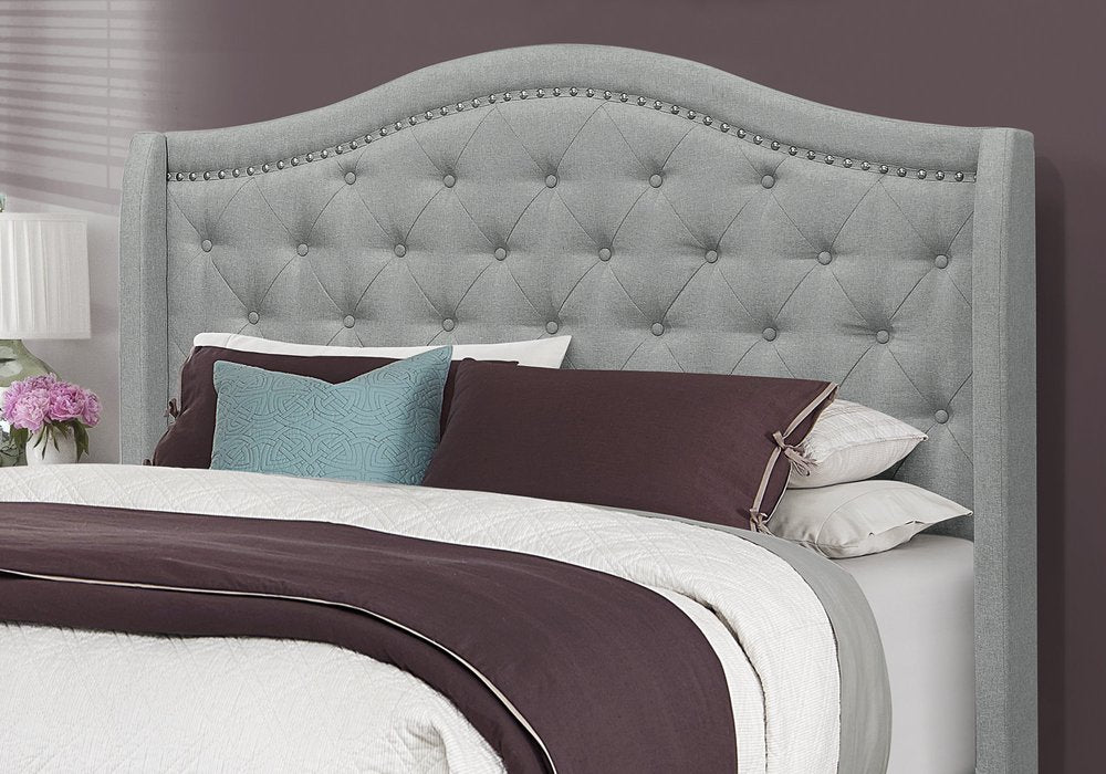 Solid wood queen bed with tufted gray linen upholstery and nailhead trim.