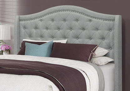 Solid wood queen bed with tufted gray linen upholstery and nailhead trim.