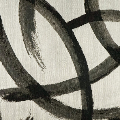 Beige pillow fabric with intersecting black brushstroke lines in an abstract pattern.