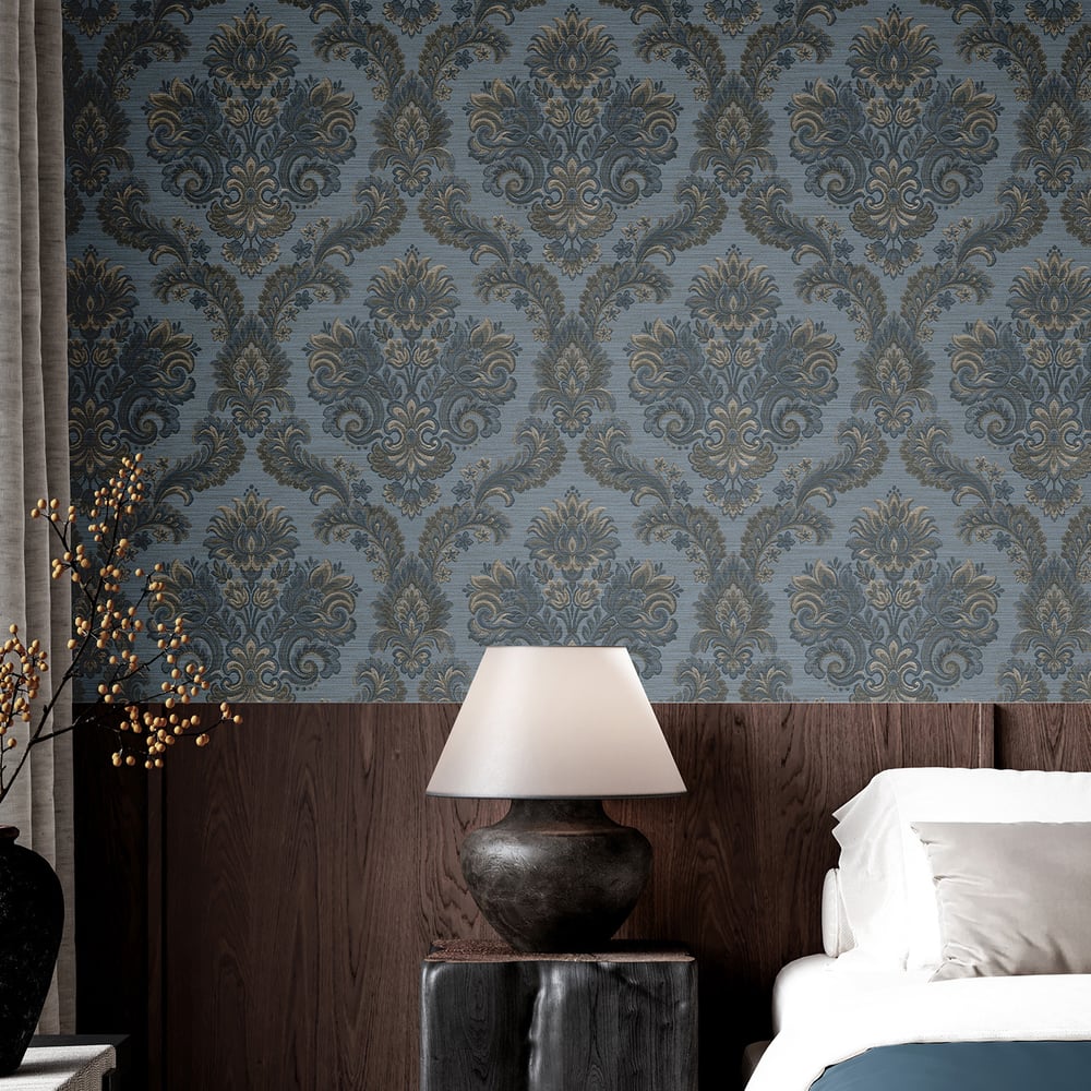 Blue damask wallpaper with dark wood paneling, ceramic bedside lamp with white shade atop a nightstand beside a white bed.