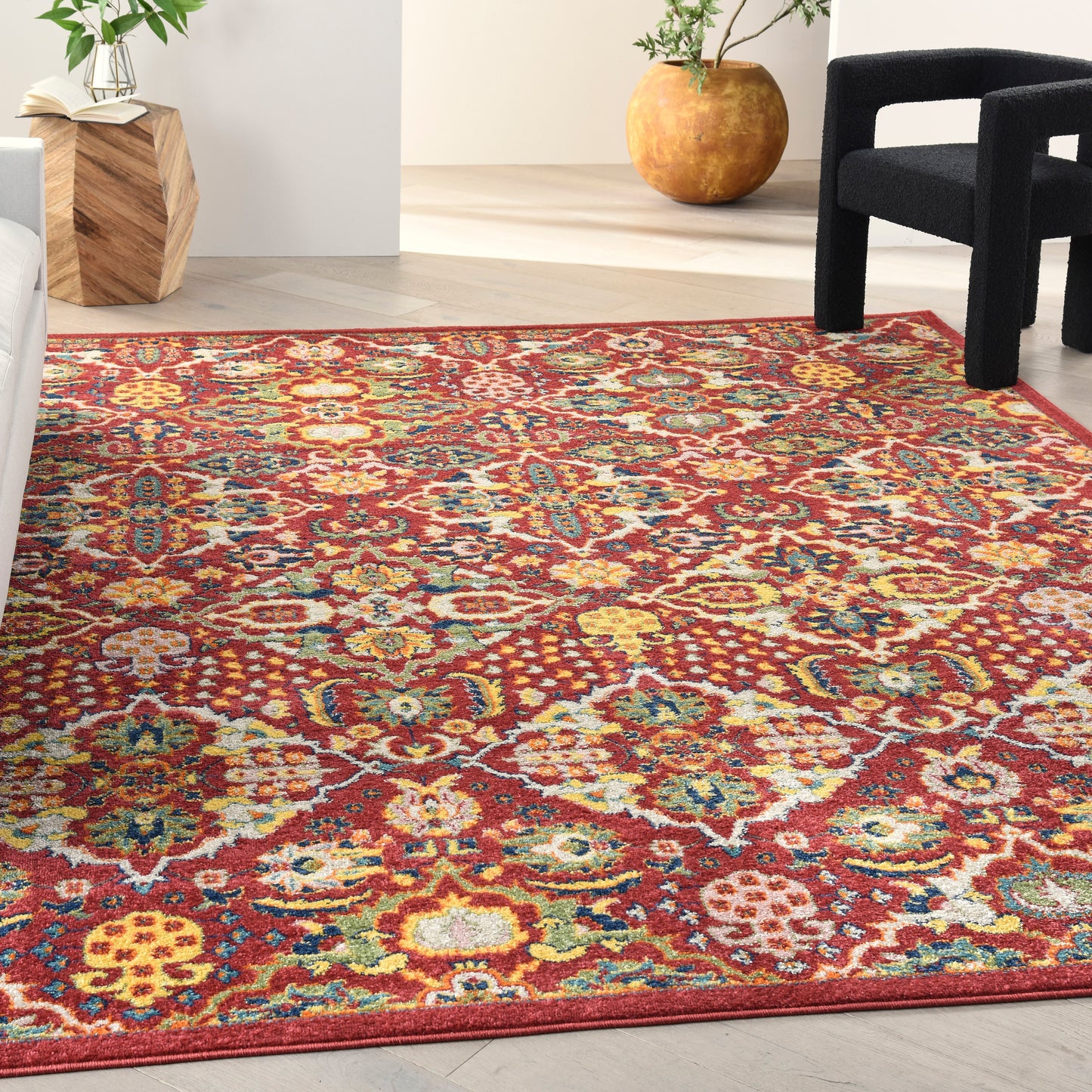 Colorful Bohemian-style woven area rug with red base and yellow, teal, cream floral motifs in a modern lounge.