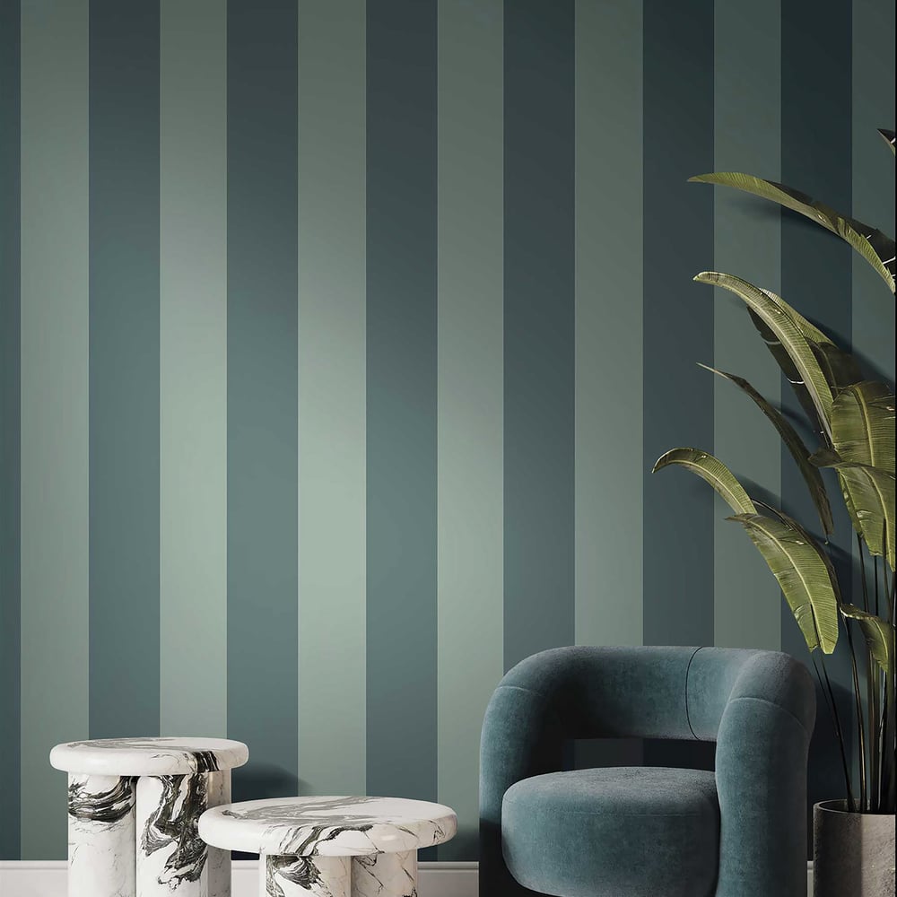 Green textured wide-stripe wallpaper on the wall; foreground shows a teal velvet curved armchair beside two white marble round side tables & a tall plant.