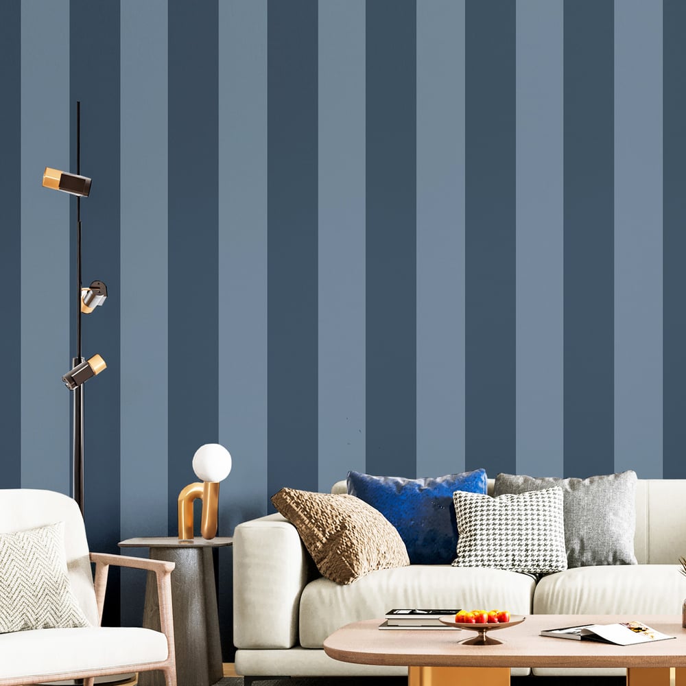 Living room with a blue vertical striped wall, beige sofa with blue and textured cushions, round wooden coffee table, and a multi-head floor lamp.
