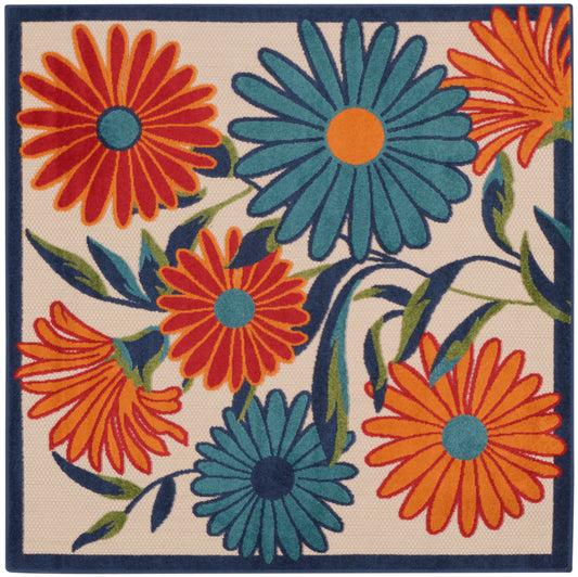 Square decorative rug with bold orange and teal daisies on beige background, navy border.