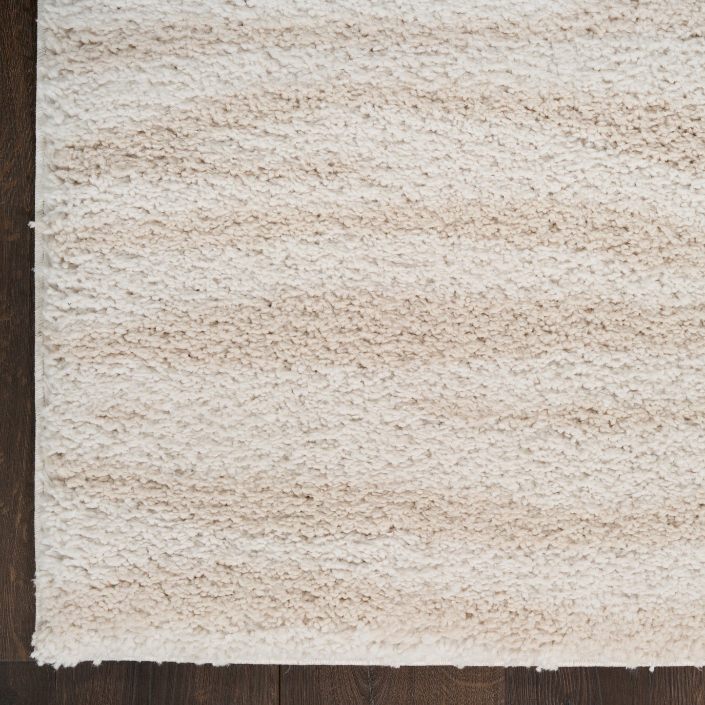 Cream beige shag rug with thick plush pile on dark wood flooring; cozy modern accent for living room or bedroom.