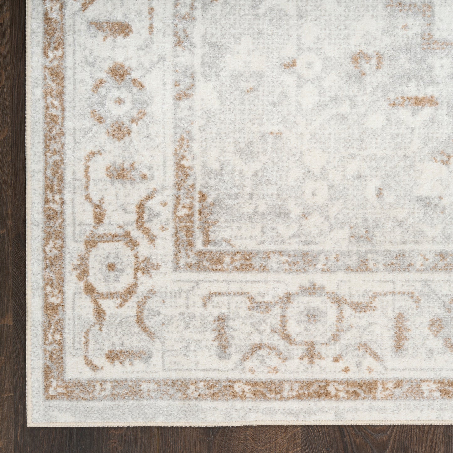 Rectangular ivory runner with tan ornamental border on dark wood floor.