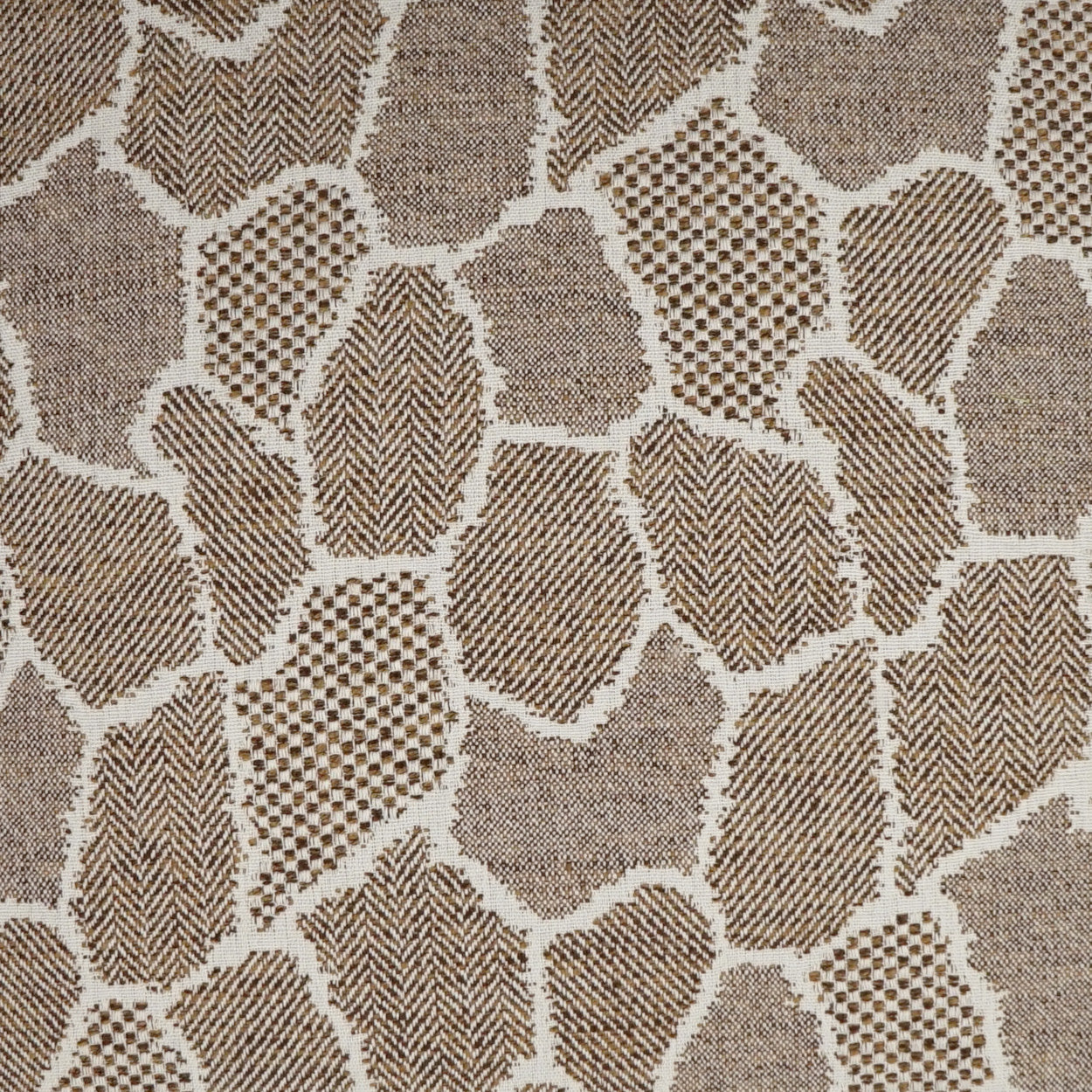 Beige and light brown woven fabric with a giraffe‑print patchwork of dotted and striped blocks; upholstery textile.